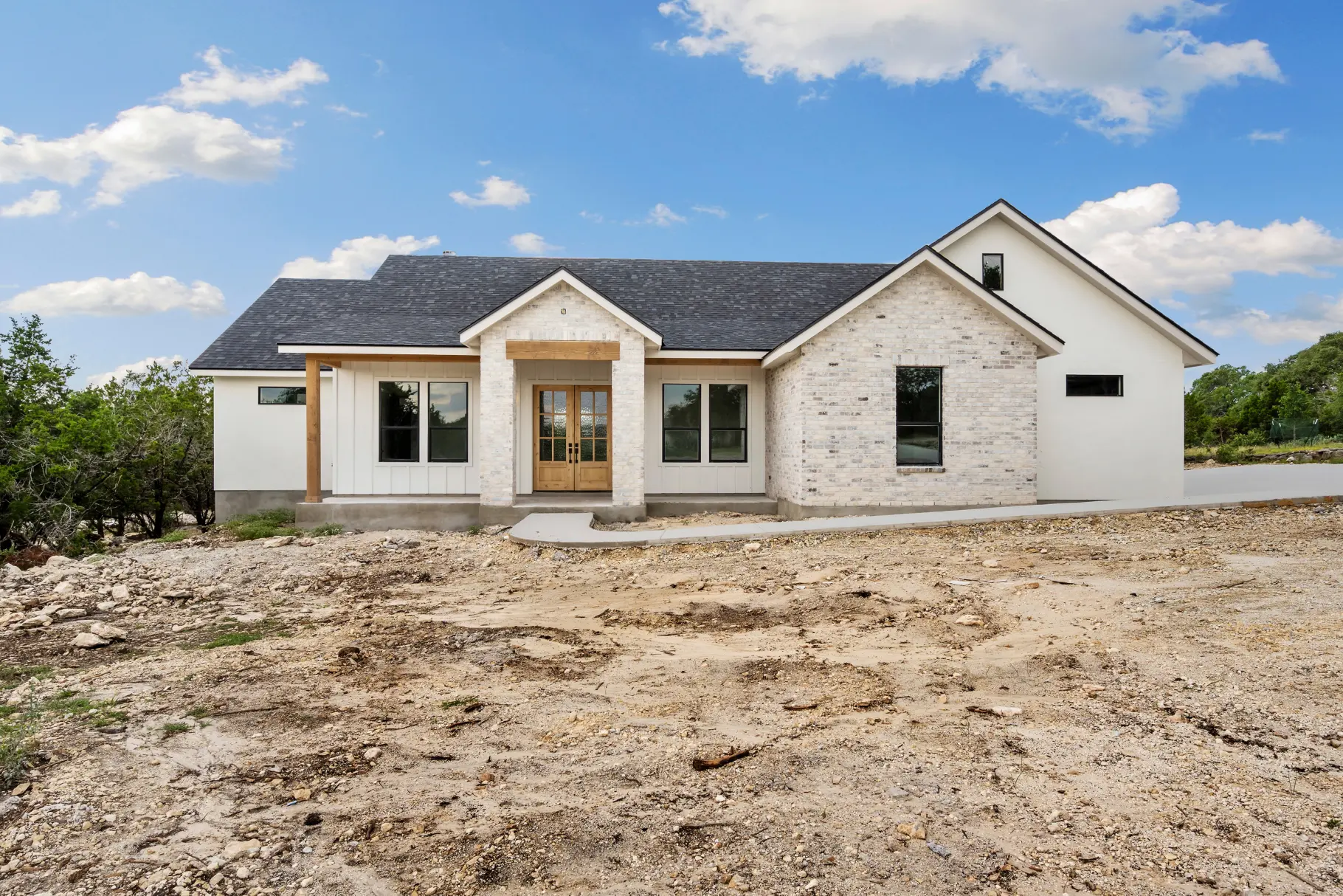 White single-storey home with a dark shingle roof on a cleared building site