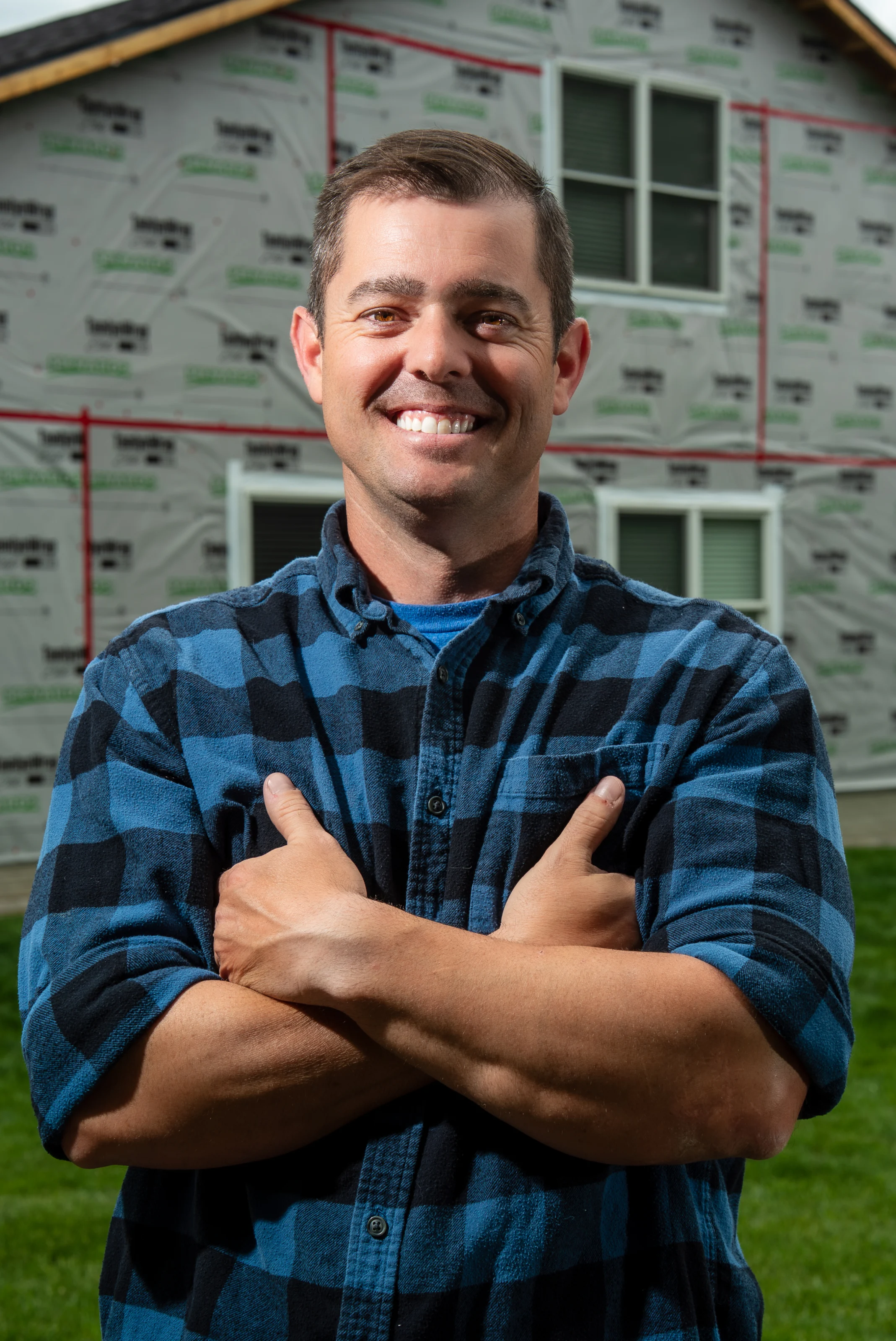 Kevin Gerken standing with arms crossed in front of a house wrapped in house wrap