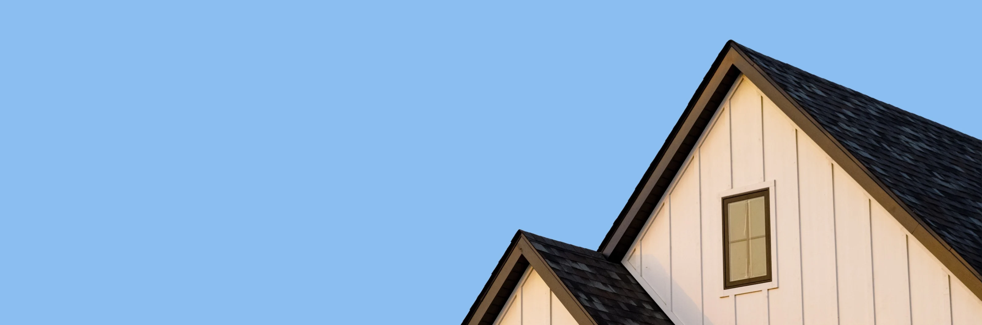 Residential home roof against a blue sky
