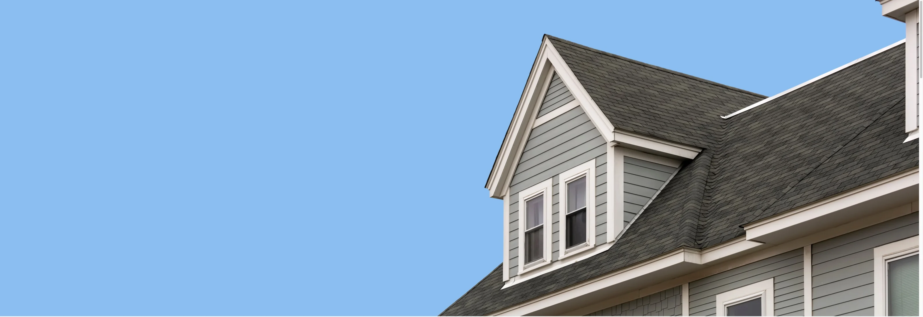 Grey roof and dormer against a blue sky