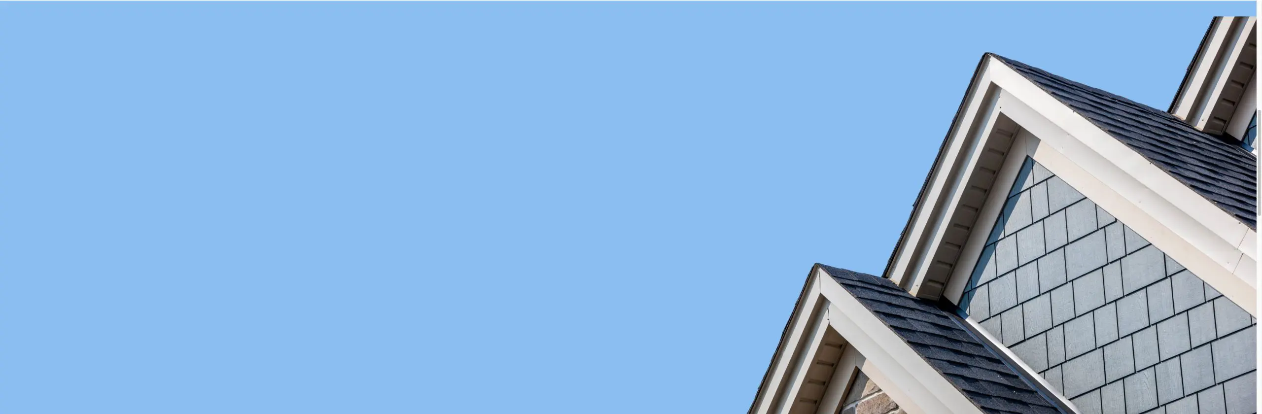 Roof gables and shingle siding against a blue sky
