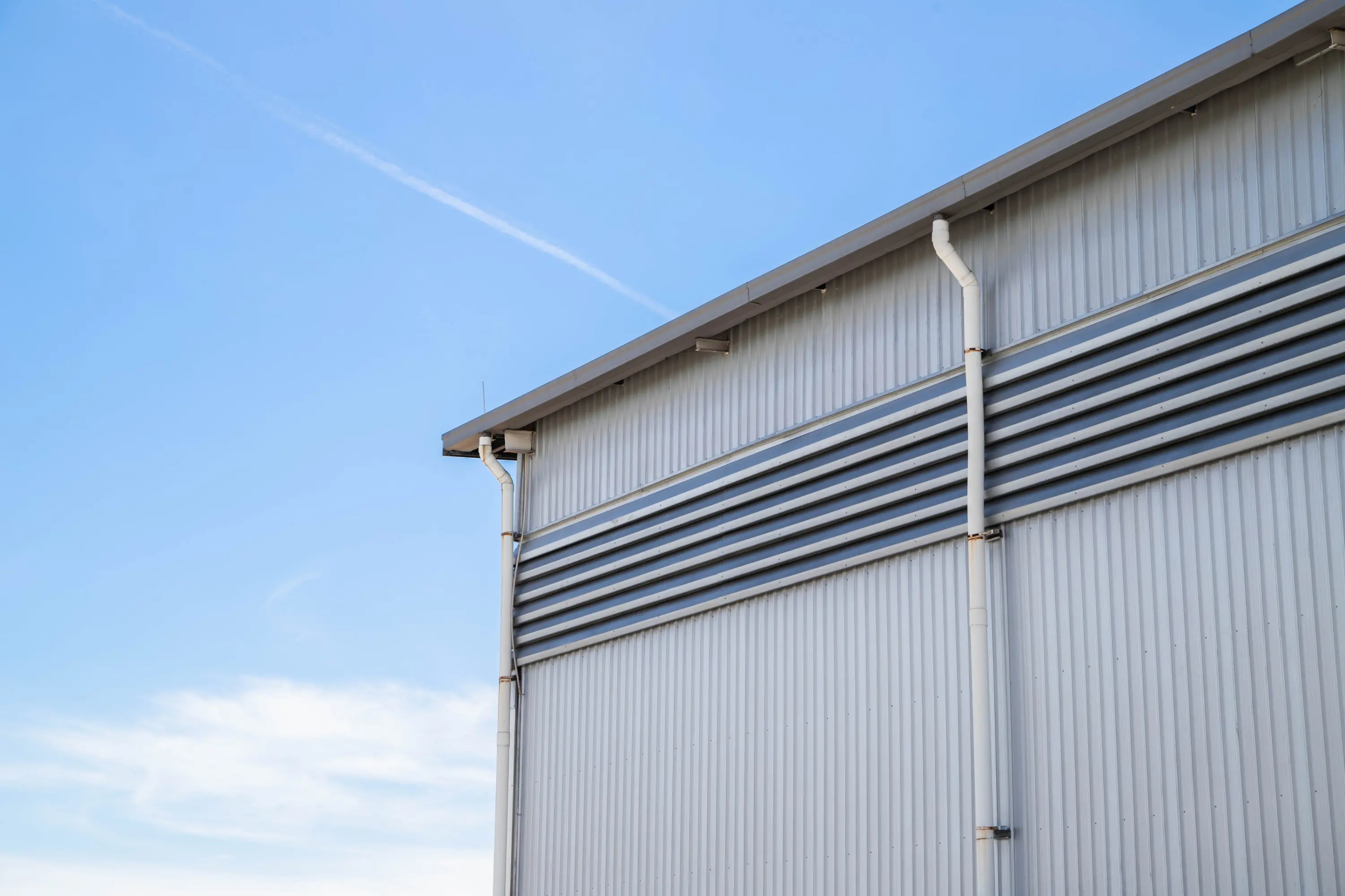 Metal gutter and downspouts on the corner of a commercial building with metal siding