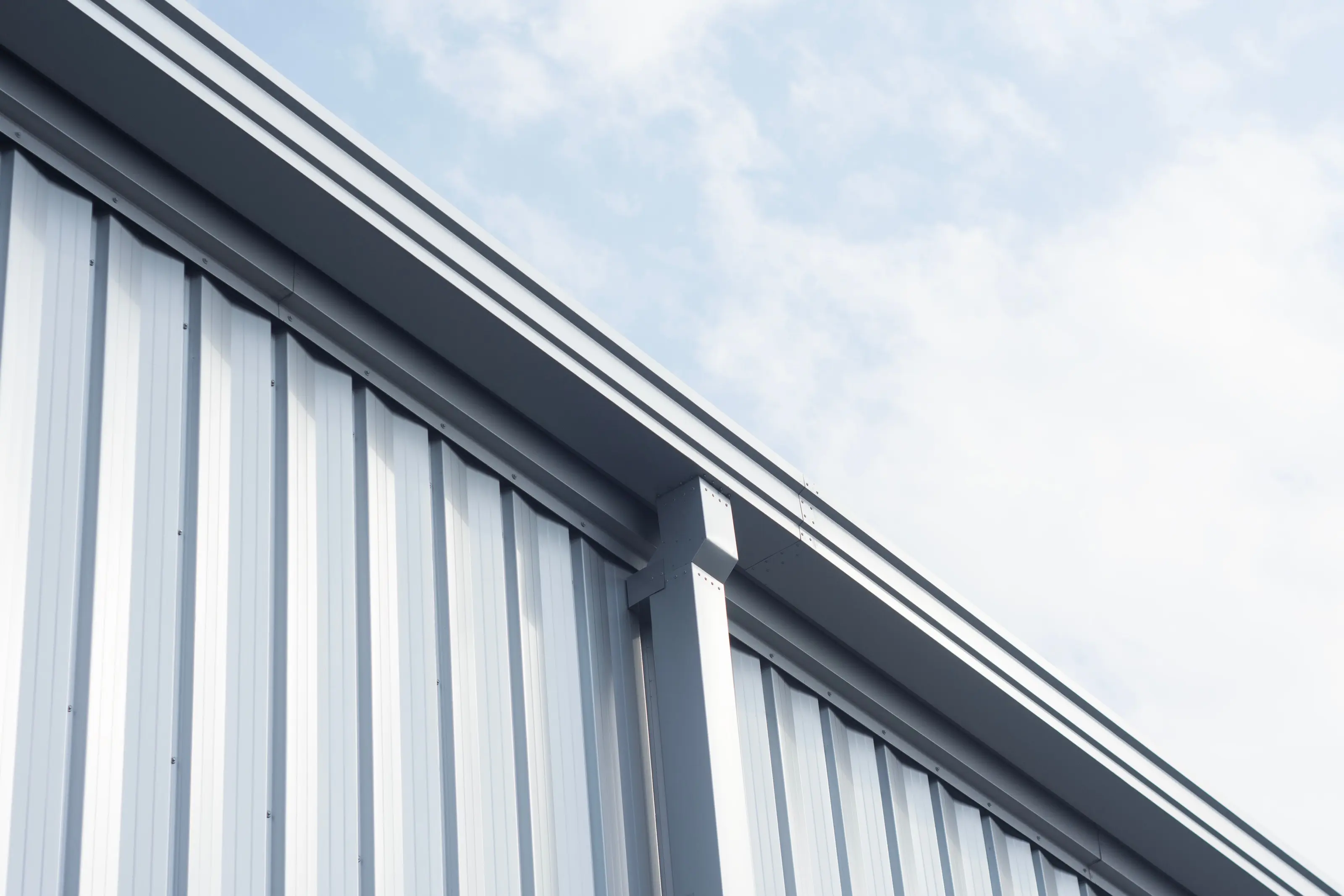 Metal gutter along the roof edge of a commercial building against the sky