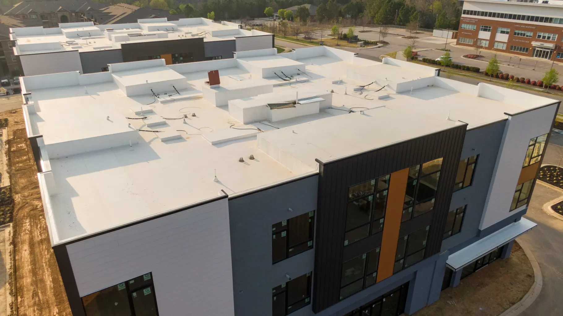 Modern multi-storey commercial building with a white flat roof, seen from above