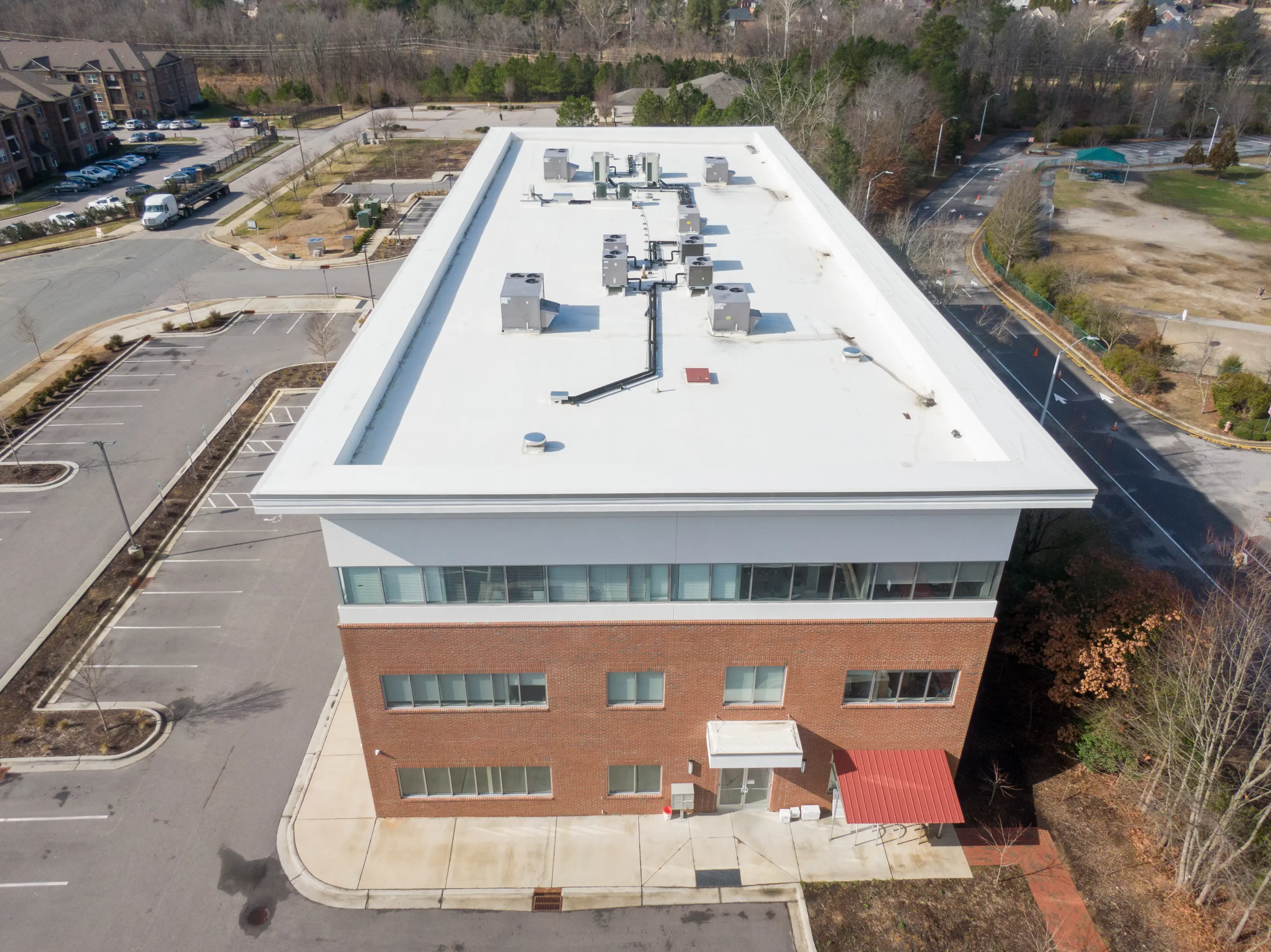 Aerial view of a brick office building with a new white membrane roof