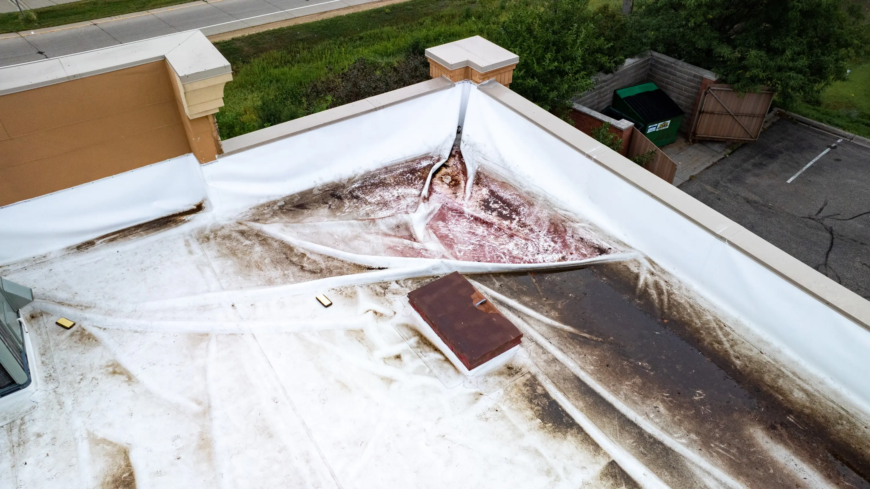 Torn and stained membrane on a commercial flat roof after a storm