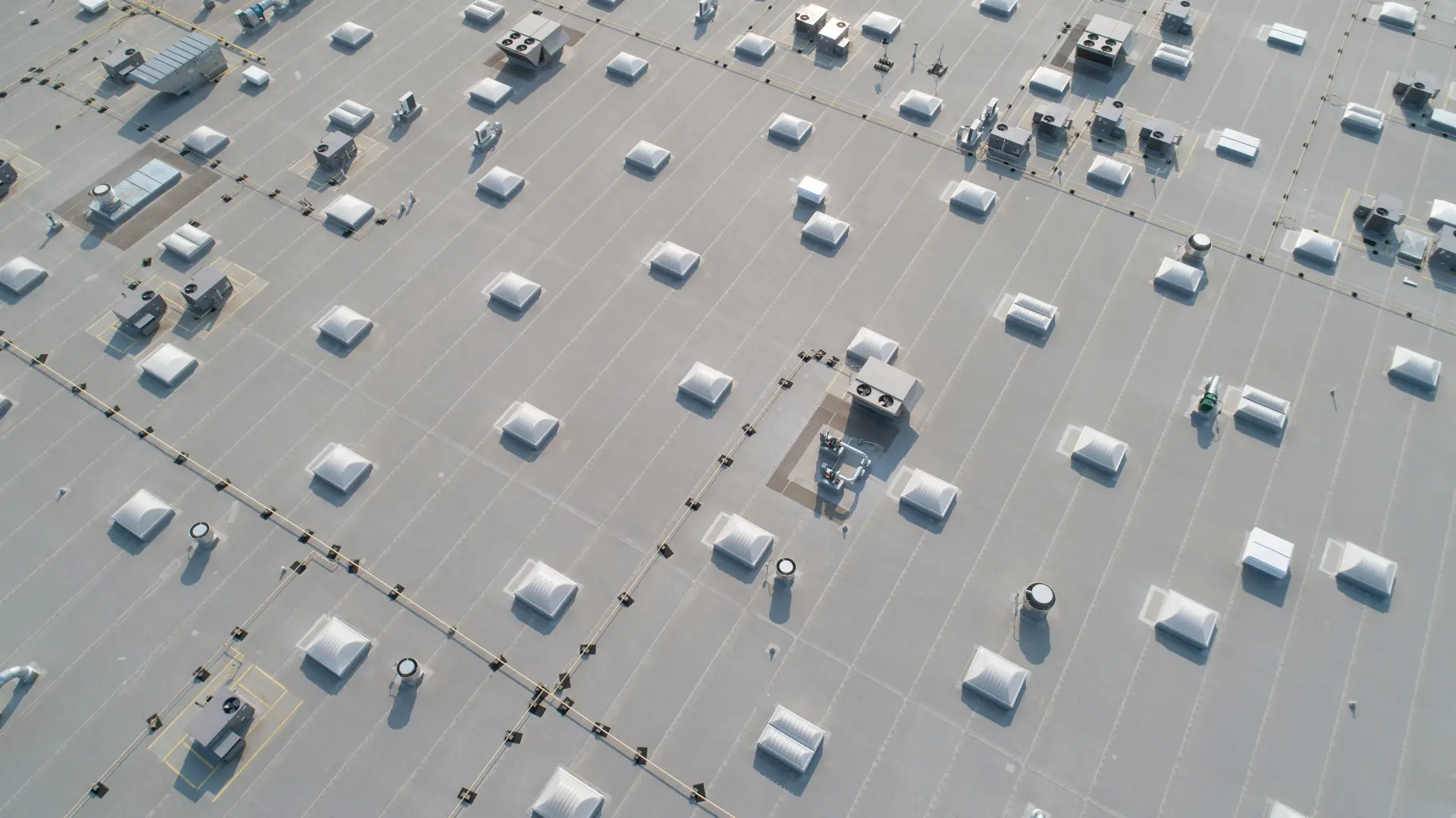 Aerial view of a grey commercial flat roof with rows of skylights