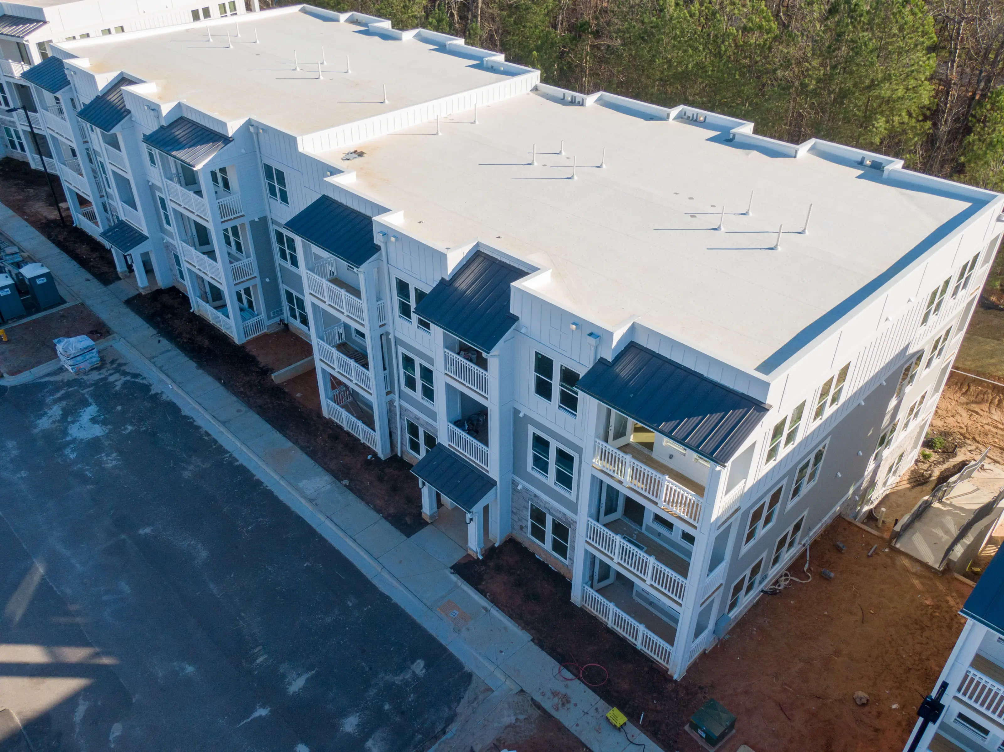Aerial view of a three-storey apartment building with a white flat roof