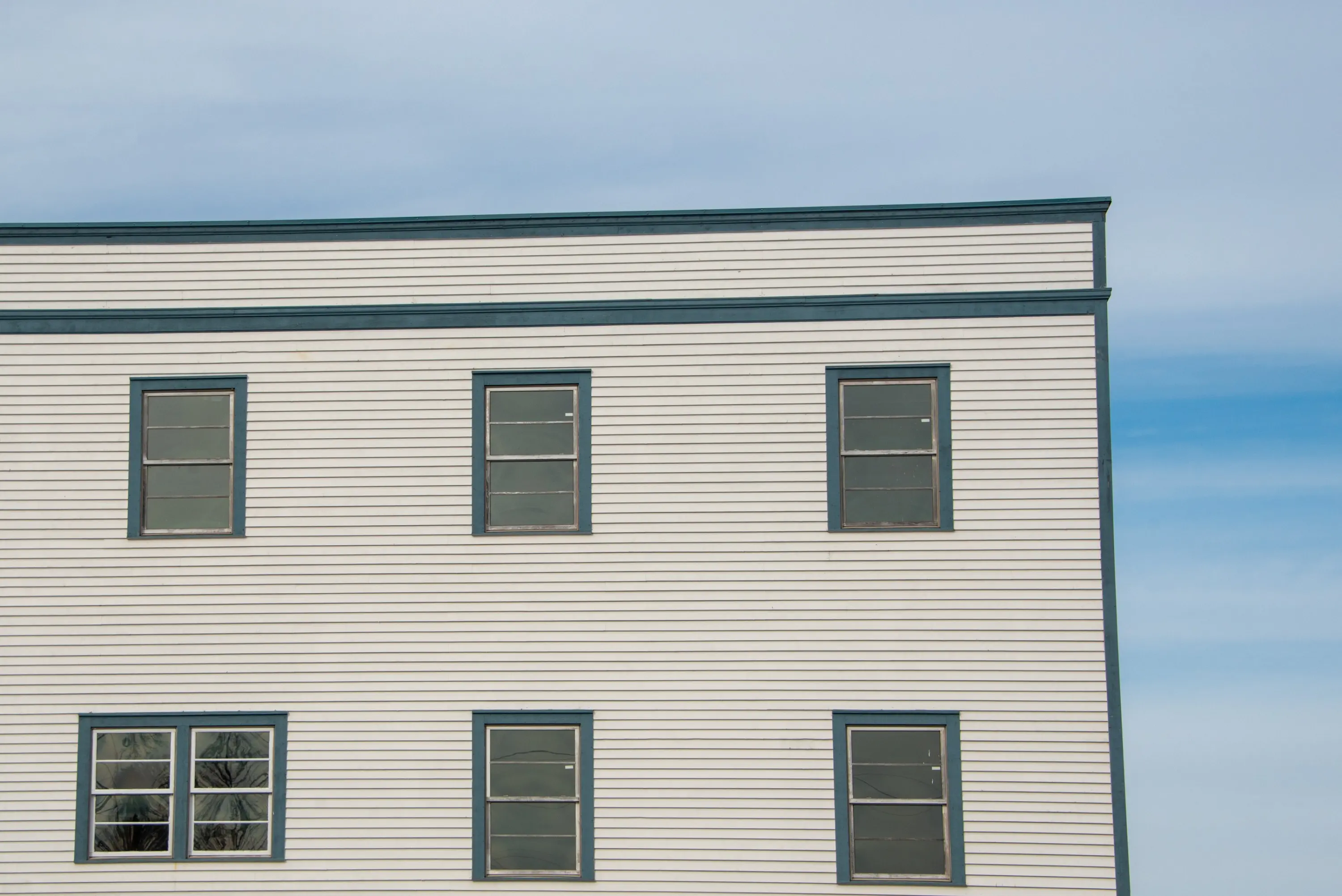 Ageing horizontal lap siding on a two-storey commercial building