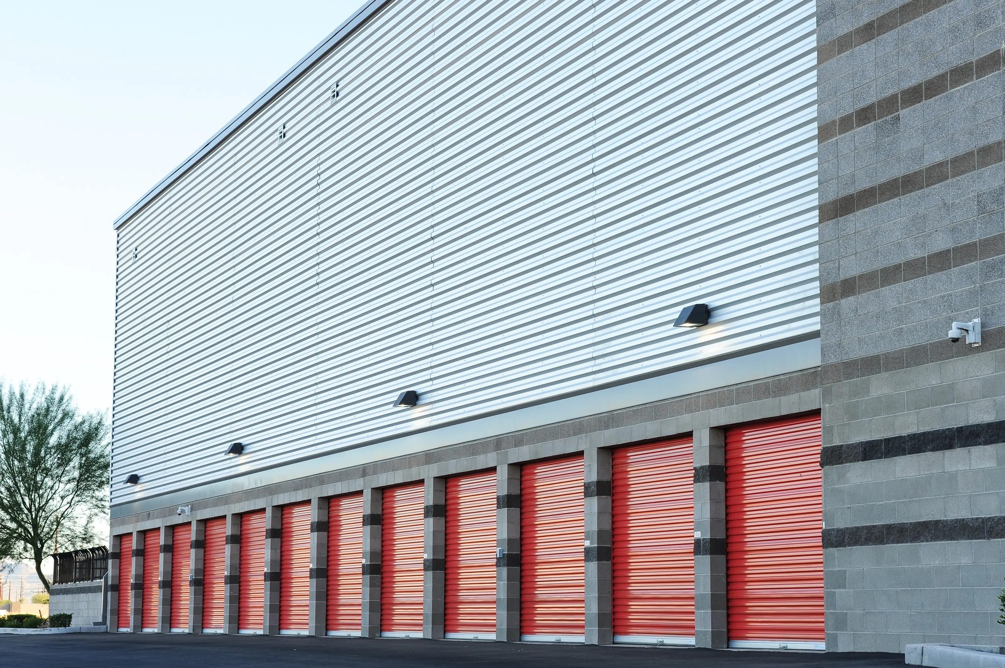 Metal-sided self-storage building with a row of red roll-up doors