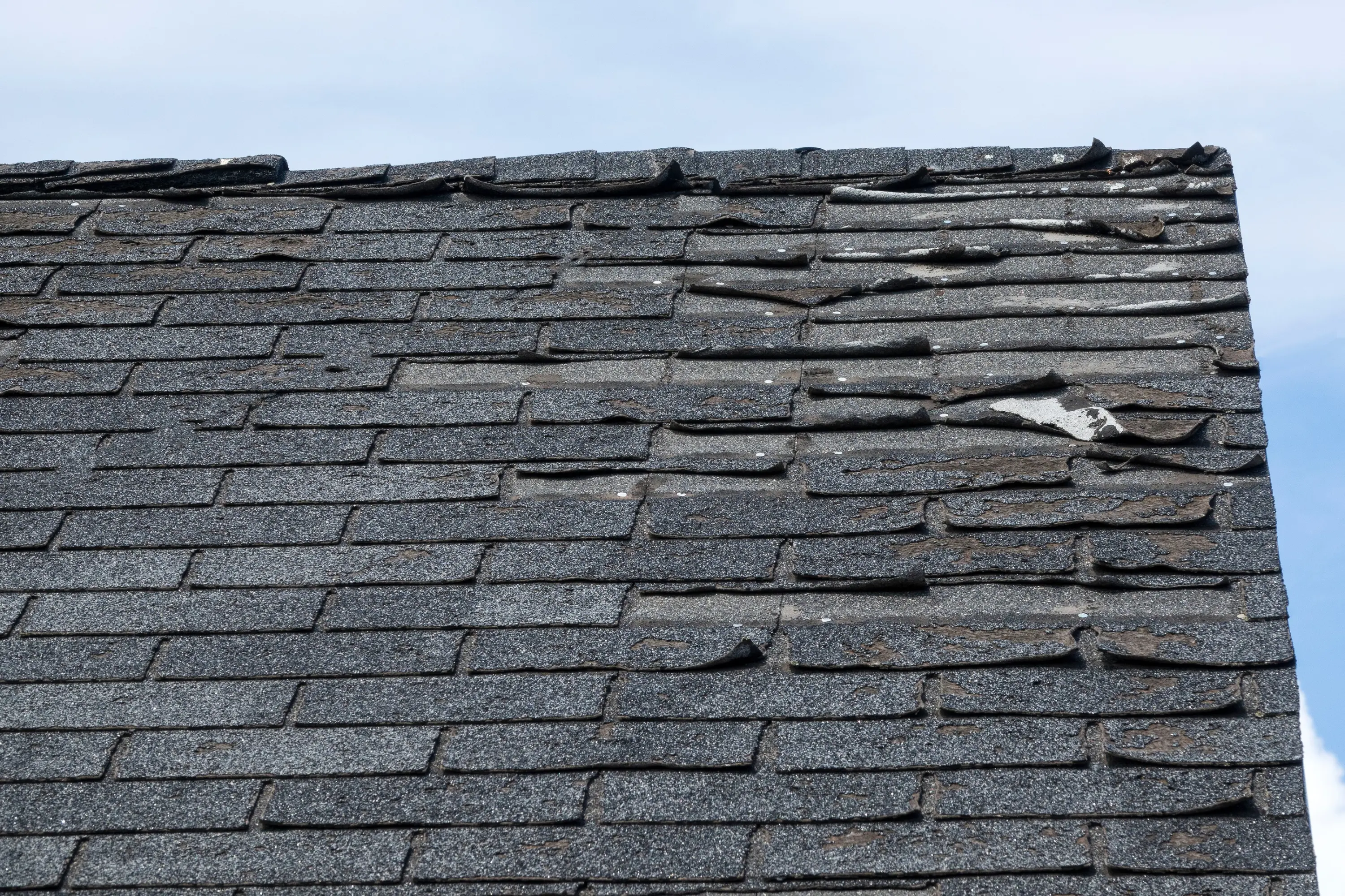 Worn, curling asphalt shingles at the end of their lifespan