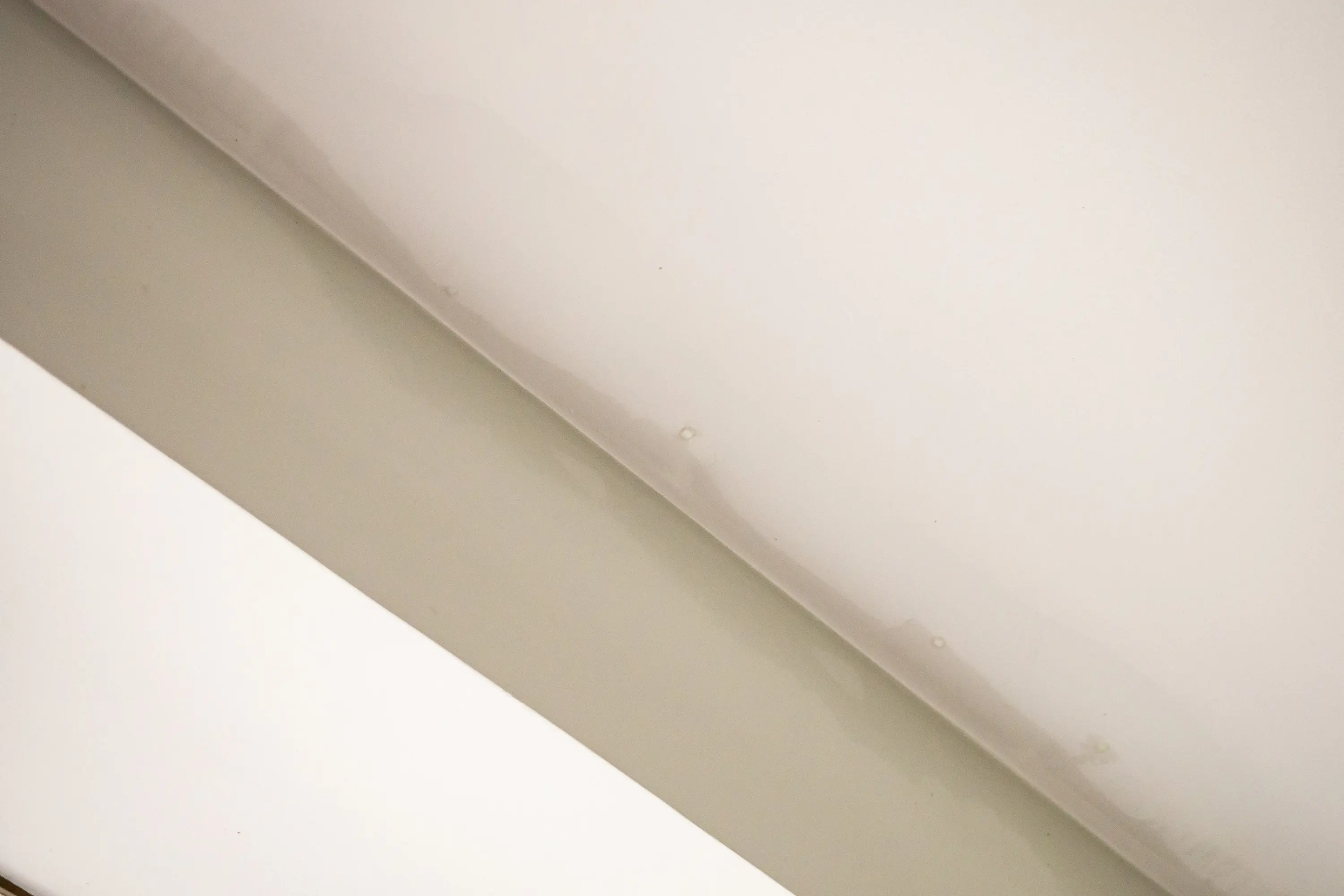Faint water stain spreading across an interior ceiling corner