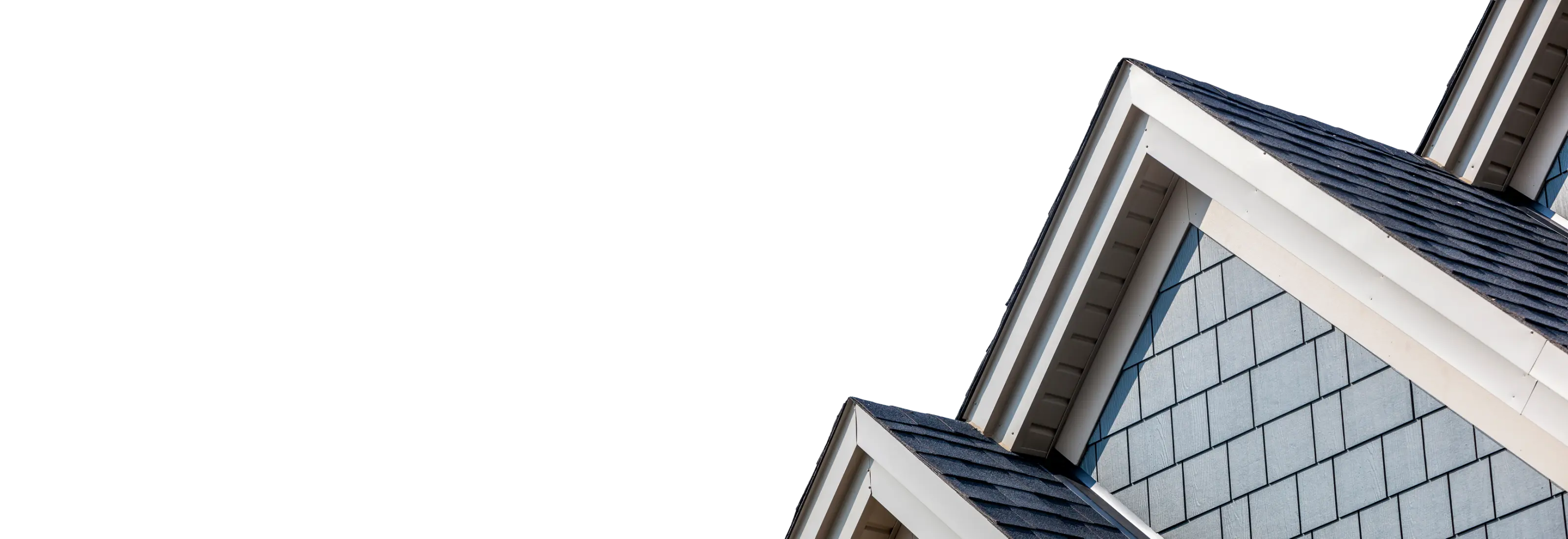 House gable with grey shingle siding and white trim against a blue sky